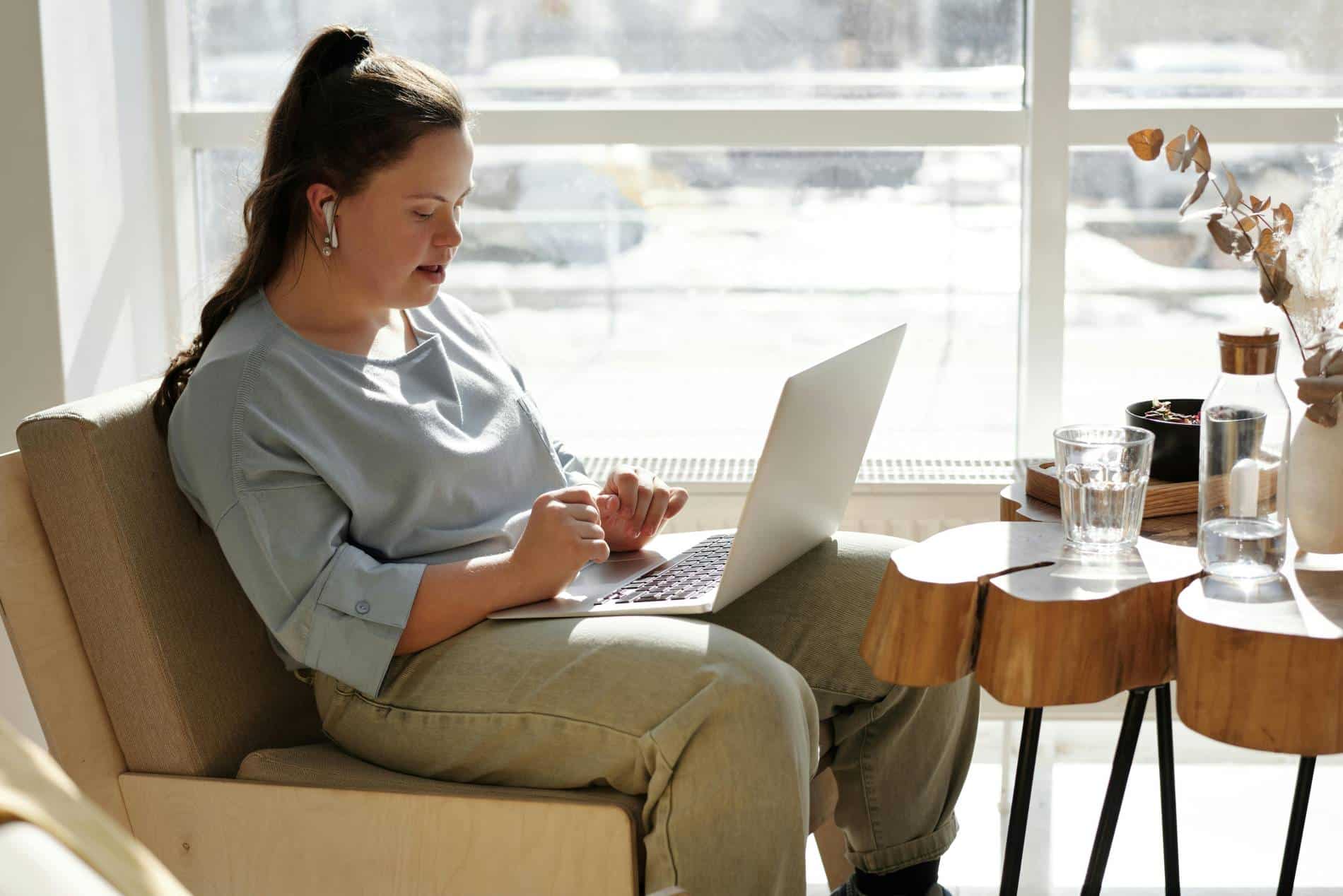 Woman sitting in a chair typing on a laptop.