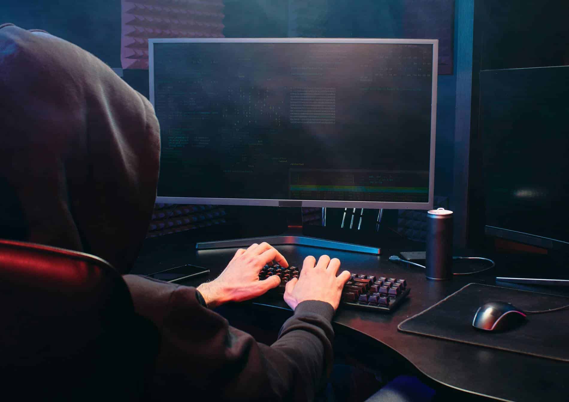 Person in a black hoodie typing on a computer keyboard.