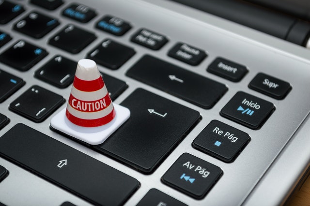 A small "Caution" cone perched humorlessly on a laptop keyboard.